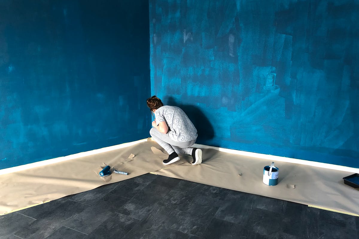 Woman In Gray Shirt And Gray Pants Painting The Walls